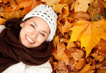 Portrait of an autumn woman lying over leaves and smiling
