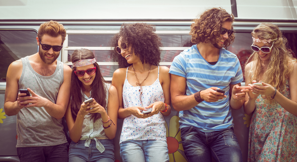 Hipster friends using their phones on a summers day