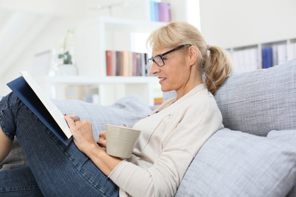 Senior woman reading book and relaxing in sofa-1
