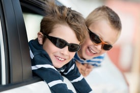 Two little boys with shades playing inside the car