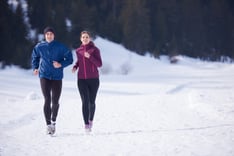 healthy young couple jogging outside on snow in forest. athlete running on  beautiful sunny winter day.jpeg